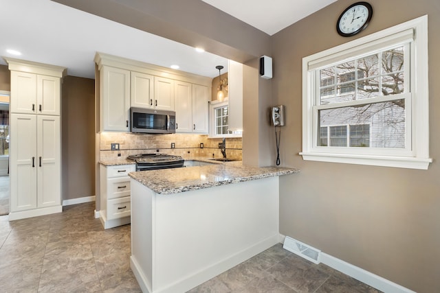 kitchen with sink, hanging light fixtures, stainless steel appliances, decorative backsplash, and kitchen peninsula