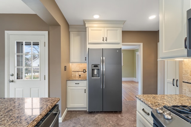 kitchen with light stone countertops, appliances with stainless steel finishes, white cabinets, and decorative backsplash