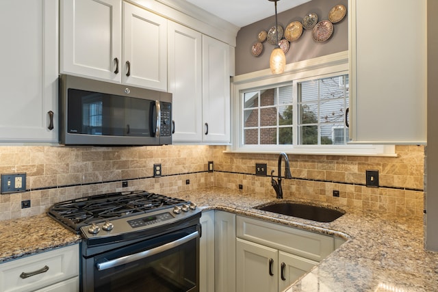 kitchen with stainless steel appliances, white cabinetry, hanging light fixtures, and sink