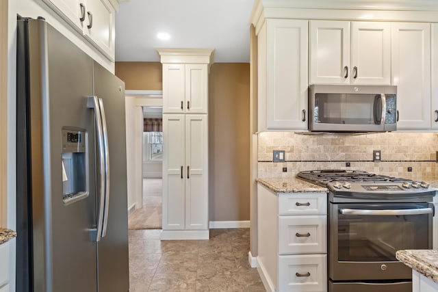 kitchen featuring appliances with stainless steel finishes, backsplash, and light stone counters