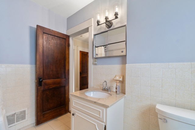 bathroom with tile patterned floors, vanity, toilet, and tile walls