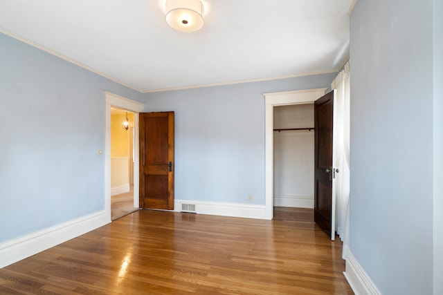 unfurnished bedroom with crown molding, hardwood / wood-style flooring, and a closet