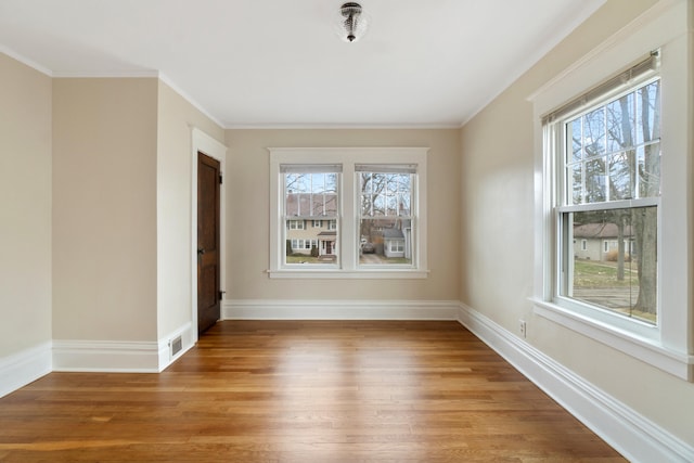 empty room featuring crown molding, plenty of natural light, and hardwood / wood-style floors