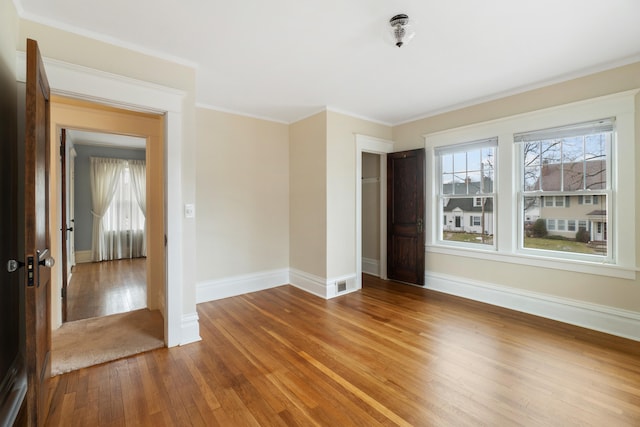 empty room with hardwood / wood-style flooring and crown molding