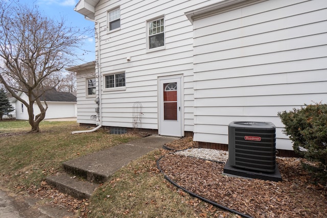 entrance to property featuring cooling unit and a lawn