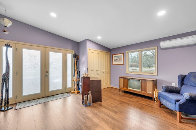 foyer featuring vaulted ceiling, wood-type flooring, a wall mounted air conditioner, and french doors