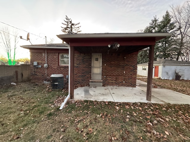 rear view of house featuring an outdoor structure, a patio area, and a lawn