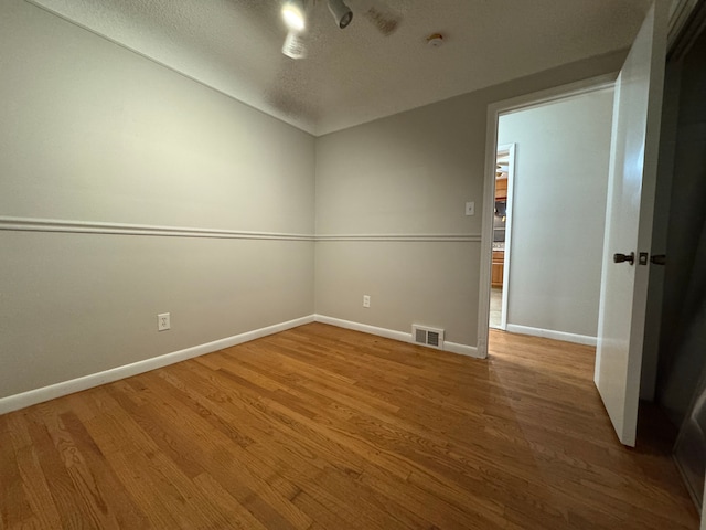 spare room with wood-type flooring and a textured ceiling