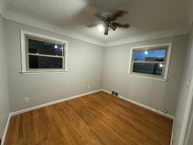 empty room featuring hardwood / wood-style flooring, a textured ceiling, and ceiling fan