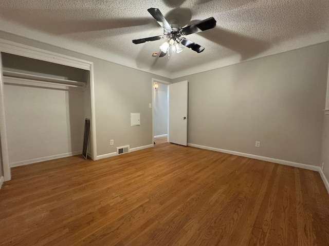 unfurnished bedroom featuring ceiling fan, hardwood / wood-style floors, a textured ceiling, and a closet