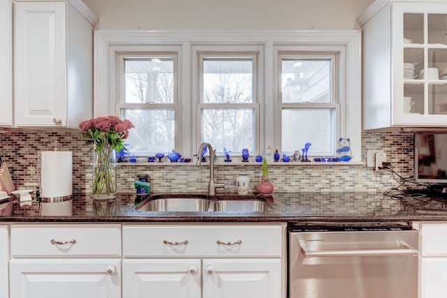 kitchen with sink, white cabinetry, dark stone countertops, dishwasher, and decorative backsplash