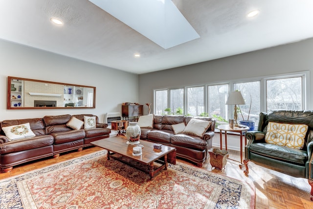 living room featuring parquet flooring, a fireplace, and a skylight