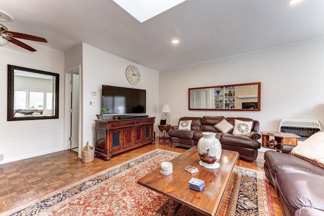 living room with heating unit, a skylight, parquet flooring, and ceiling fan