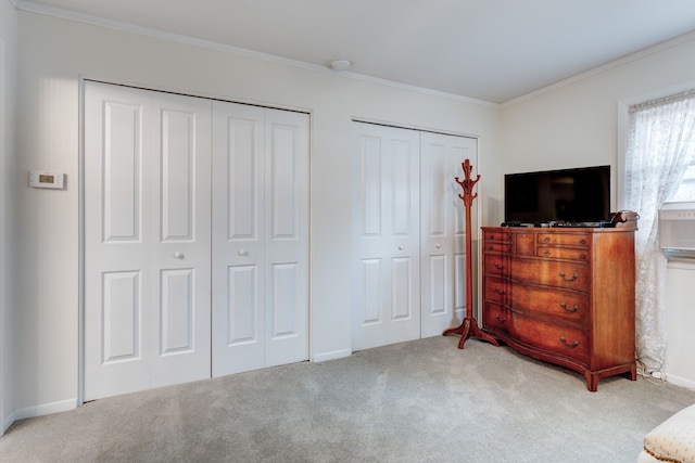 carpeted bedroom featuring crown molding and two closets