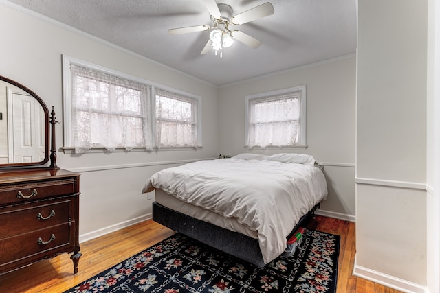 bedroom with ornamental molding, ceiling fan, a textured ceiling, and light wood-type flooring