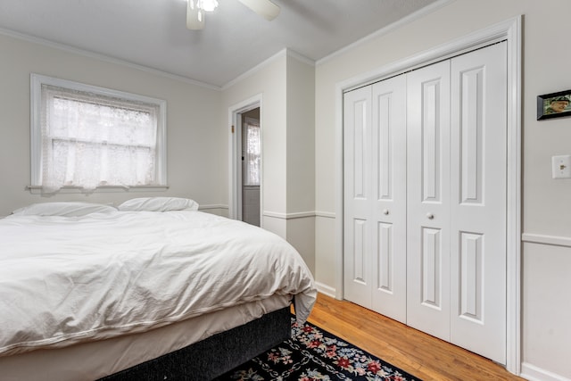 bedroom with wood-type flooring, ceiling fan, crown molding, and a closet