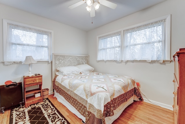 bedroom featuring multiple windows, hardwood / wood-style floors, and ceiling fan