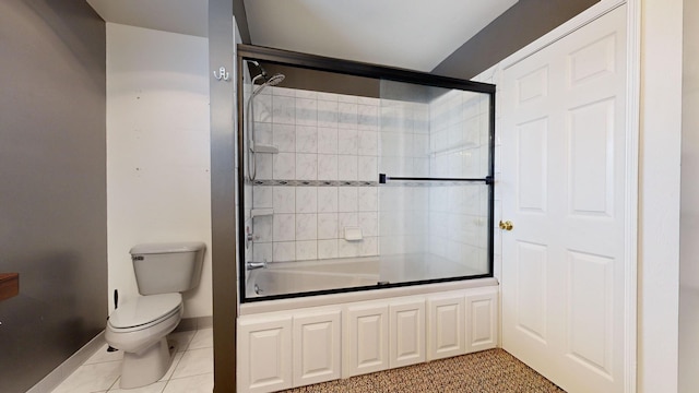 bathroom featuring tile patterned flooring, enclosed tub / shower combo, and toilet