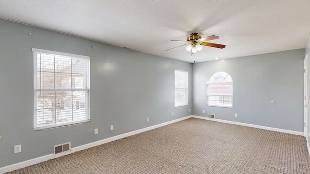 spare room featuring ceiling fan, carpet, and a textured ceiling