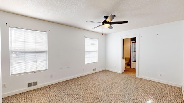 carpeted spare room featuring ceiling fan and a textured ceiling