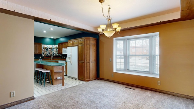 kitchen with a breakfast bar area, decorative light fixtures, light colored carpet, a notable chandelier, and white appliances