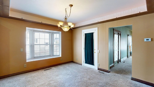 carpeted spare room featuring a chandelier