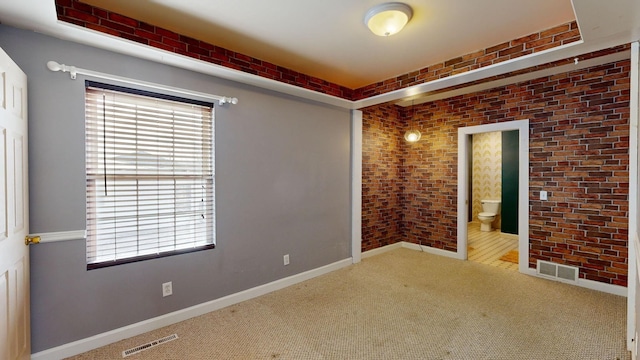 carpeted empty room with brick wall