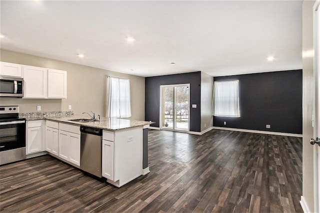 kitchen featuring white cabinetry, appliances with stainless steel finishes, dark hardwood / wood-style floors, and light stone countertops