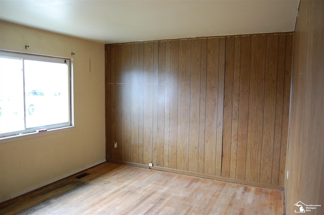 unfurnished room featuring wooden walls and light hardwood / wood-style flooring