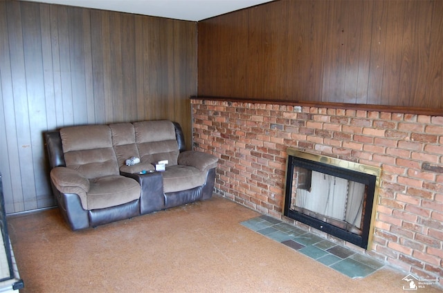 living room with carpet, a brick fireplace, and wood walls