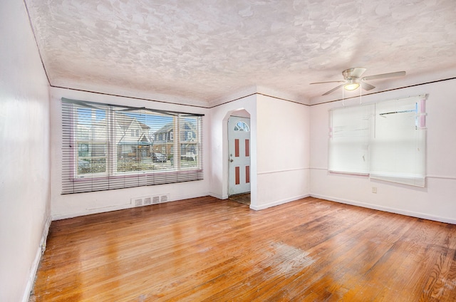 unfurnished room with ceiling fan, light hardwood / wood-style flooring, and a textured ceiling