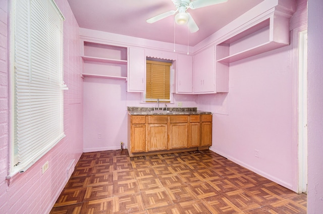 kitchen featuring ceiling fan, dark parquet flooring, light stone countertops, and sink