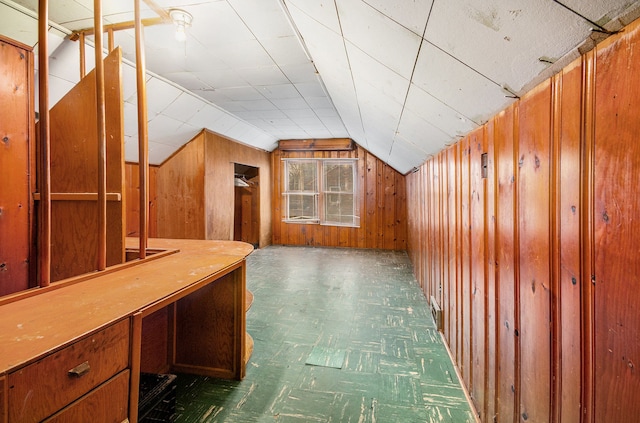 additional living space featuring vaulted ceiling and wood walls