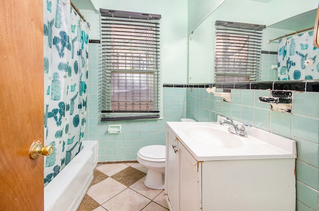 full bathroom featuring toilet, tile walls, vanity, shower / bath combo with shower curtain, and tile patterned flooring