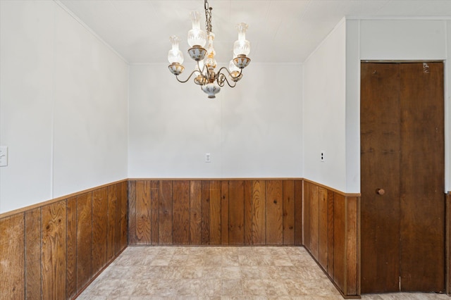 spare room with a notable chandelier and wood walls