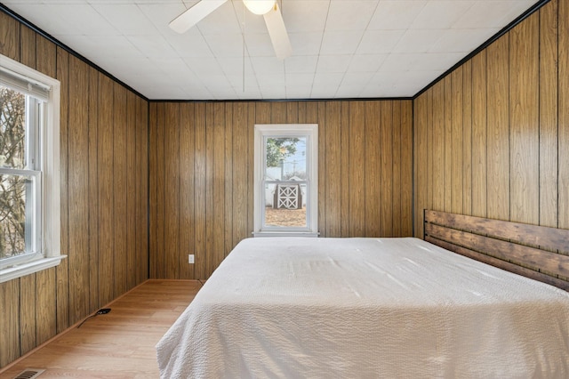 bedroom with wooden walls and light hardwood / wood-style floors