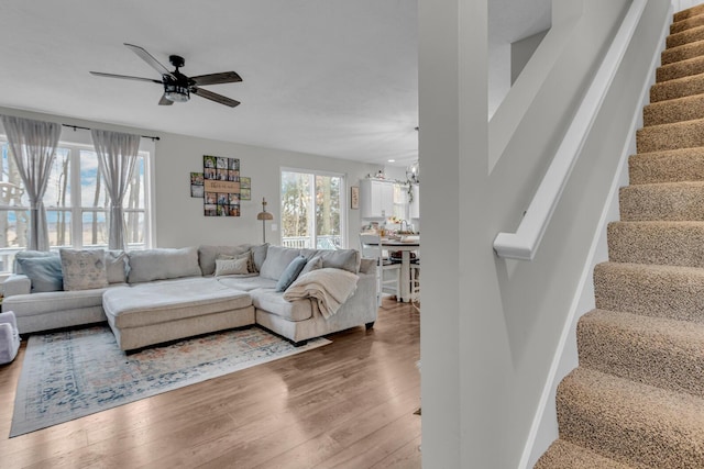 living room with ceiling fan with notable chandelier and hardwood / wood-style floors