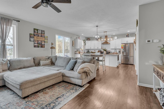 living room featuring ceiling fan with notable chandelier and hardwood / wood-style floors