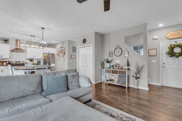 living room with dark hardwood / wood-style flooring and ceiling fan with notable chandelier