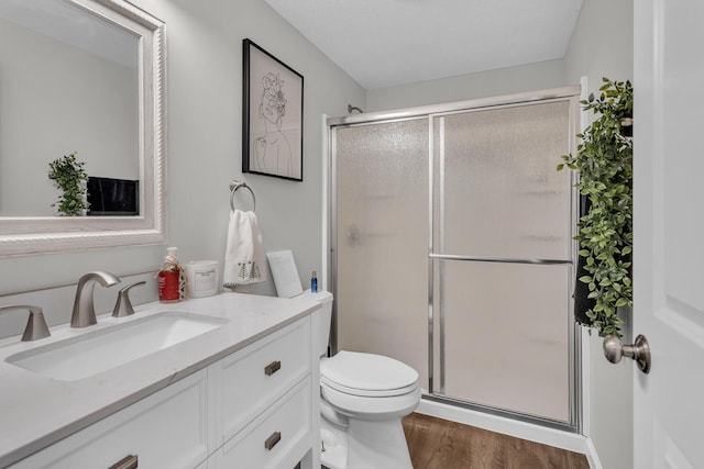 bathroom with walk in shower, vanity, toilet, and hardwood / wood-style floors