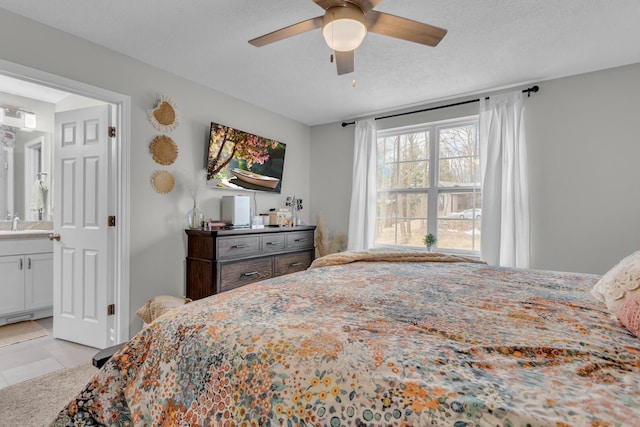 bedroom with ceiling fan, ensuite bathroom, sink, and a textured ceiling