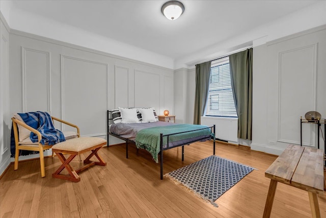 bedroom featuring radiator heating unit and light hardwood / wood-style floors