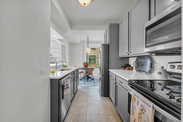 kitchen featuring decorative light fixtures, sink, stainless steel appliances, and gray cabinetry