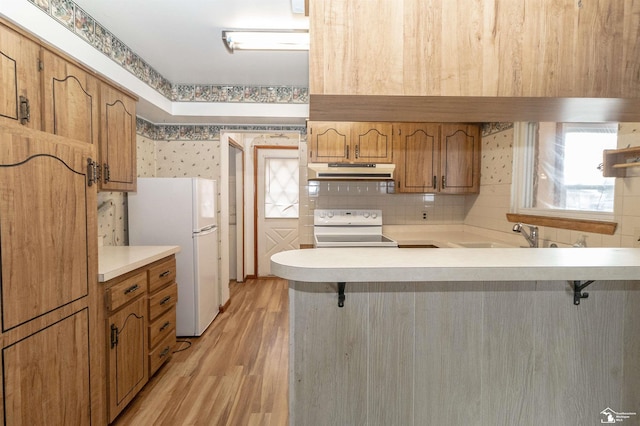 kitchen with a breakfast bar area, sink, white fridge, and stove