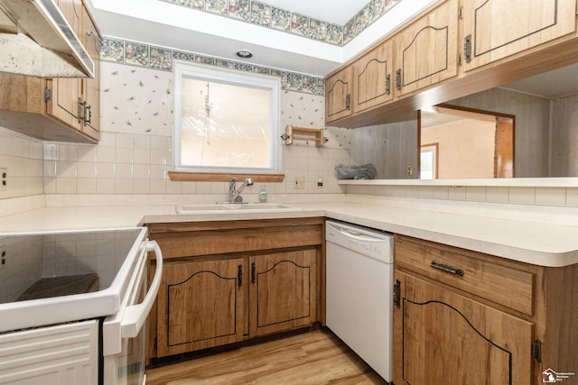 kitchen featuring sink, backsplash, white appliances, and light hardwood / wood-style floors