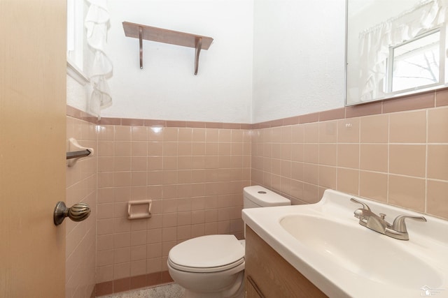 bathroom featuring vanity, tile walls, and toilet