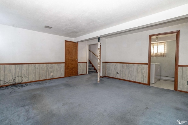 interior space with light colored carpet, a textured ceiling, and wood walls