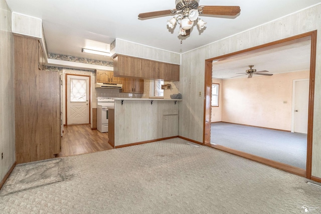 kitchen with light carpet, a breakfast bar, white electric range, and kitchen peninsula