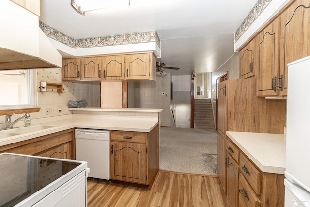 kitchen featuring sink, custom exhaust hood, kitchen peninsula, white appliances, and light hardwood / wood-style floors