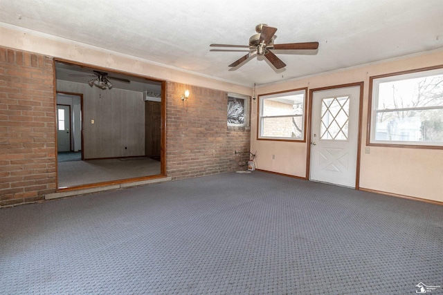 carpeted spare room with brick wall, a healthy amount of sunlight, and ceiling fan